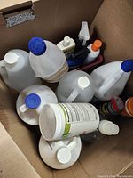 Top view of cardboard box showing gallon jugs, tub container, aerosol cans, spray and pump bottles
