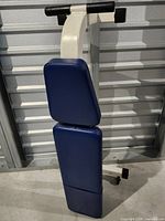 Full view of folded adjustable bench showing blue pads and white frame