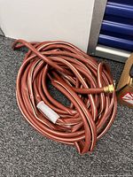 Coiled red rubber hose with brass fitting