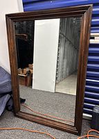 Full view of rectangular wood-framed mirror standing upright