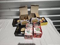 Lot overview showing string lights in open boxes, four black boxes of replacement bulbs, and two red boxes of fire starters