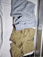 Light blue drawstring and khaki chino shorts laid flat