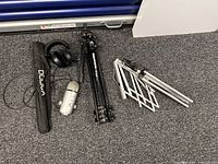 Group shot of microphone, headphones, Dolica monopod in sleeve, Manfrotto tripod, folded boom stand