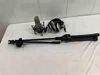 Microphone in shock mount, headphones, collapsed mic stand on table