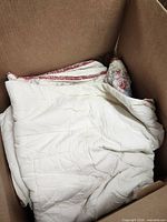 white quilt with floral trim folded in box