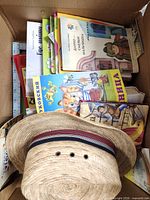 Box containing stack of Russian children's books and straw hat