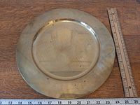 Front view of brass charger plate with ruler showing 12 inch diameter