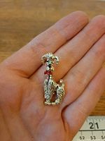 Front view of silver poodle brooch on hand showing red bow and overall size