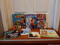 All seven children’s books lined on wooden surface with ruler for scale