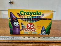 Front view of closed Crayola 96-count crayons box with branding and sharpener note
