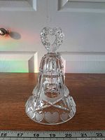 Full view of crystal bell showing heart handle, cut facets, frosted heart band, ruler for scale