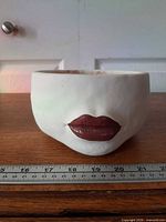 Front view showing ivory planter and red lips design with ruler for scale