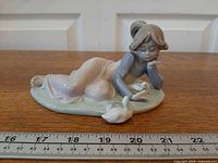 Front view of figurine showing girl, ducks and base with ruler indicating length