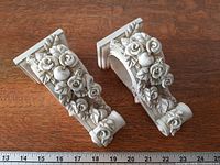 pair of plaster corbel curtain rod brackets with ruler for scale