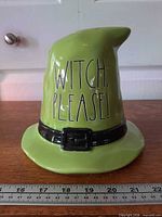 Front view of ceramic witch hat showing text and belt detail with ruler for scale