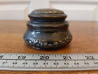 Front view showing overall form and floral relief with ruler for scale