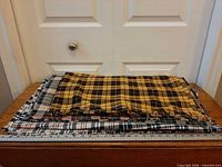 Stack of assorted plaid flannel fabric lengths on table