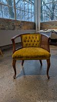 Full front view of yellow tufted chair with wood frame and cabriole legs
