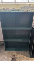 Full front view of green handmade bookshelf with three shelves