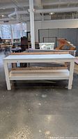 front view showing entire white wooden workbench with lower shelf