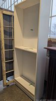 Full view of white Billy bookcase angled, shows side panel and two shelves installed