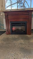Front view of wood mantel and electric firebox powered on showing flame effect