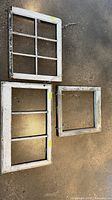 Three distressed wooden window frames laid on floor