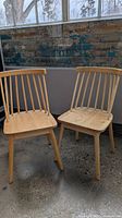 Two light wood chairs angled together showing full design
