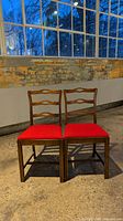 Front view of the pair of wooden dining chairs with red seats