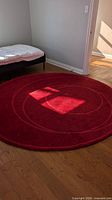 Full view of red circular carpet placed on hardwood floor