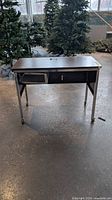 Front view of metal desk showing laminate top, open drawer shelf, casters