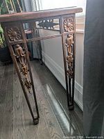 Side view highlighting ornate floral leg detail and stretcher