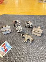 Front view showing both pairs of cufflinks, elephant charm, crest pin area and scale stamp