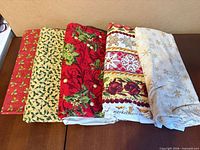 Five folded Christmas quilting cotton pieces laid out side by side