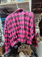 Back view of pink and black diamond pattern lightweight jacket with drawstring hem on hanger