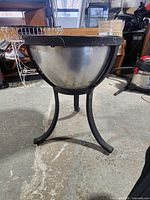 Overall view of stainless firebowl on three-leg stand