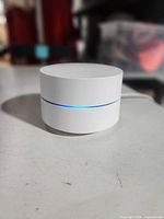 Front angled view of Google Wifi router showing LED band lit