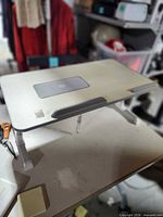 Top view of laptop tray showing surface, laptop stop bar, fan vent and compartment