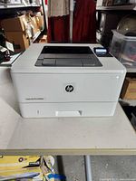 Front and top view of HP LaserJet Pro M402n printer showing exterior condition and paper tray