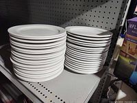 two tall stacks of white plates on shelf