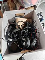 Top view of cardboard box filled with tangled wired headphones