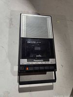 Front view showing speaker grille, cassette door, control buttons and handle