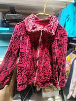 Front view showing red and black patterned zip jacket with full zipper and collar