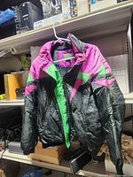 Front view of black, magenta, green Inside Edge snowboard jacket hanging