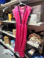 Front view of pink gown hanging on hanger showing lace trim and length