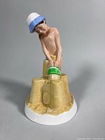 Front view of figurine showing boy, bucket and sandcastle