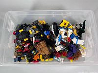 Plastic bin filled with assorted LEGO bricks, vehicles and minifigure parts