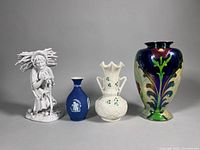 Group shot of all four items: figurine, Wedgwood bud vase, Belleek shamrock vase, Bursley Ware vase