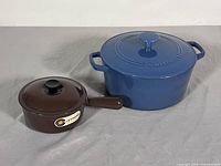 Le Creuset brown saucepan and Cuisinart blue Dutch oven side by side with lids on