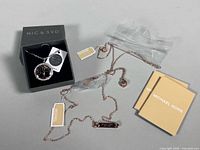 Overview showing both necklaces, Michael Kors paperwork and Nig & Syd box